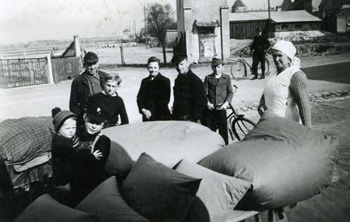 Historisches Bild von Mitarbeitern eines kleinen Daunendeckenproduzenten vor prallen Säcken